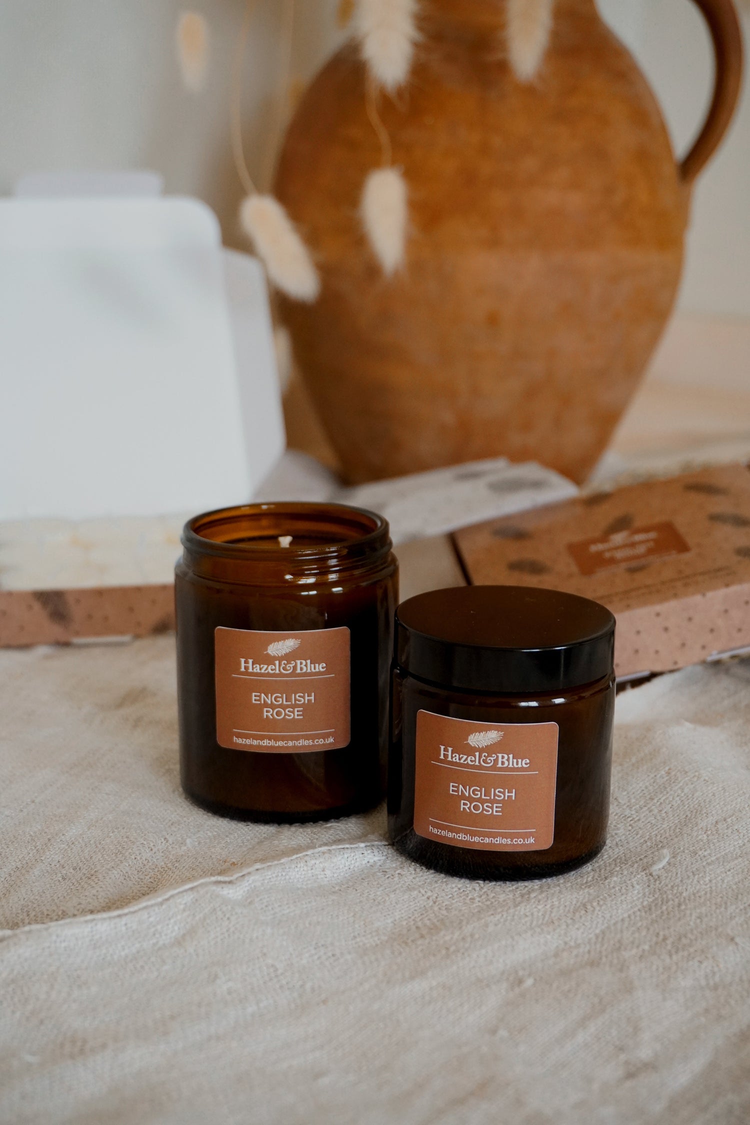  Two amber jar candles (180ml and 120ml) from our Signature Collection with taupe labels, featuring the English Rose scent. Set in a soft, elegant scene, the warm glow enhances the delicate, floral fragrance, evoking timeless luxury and tranquillity.